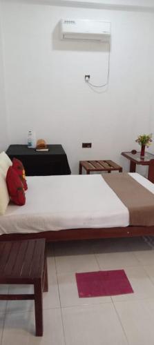 a bedroom with a large bed and a bench at Bee and Birds Hotel in Polonnaruwa