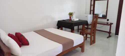 a bedroom with a bed and a table and a desk at Bee and Birds Hotel in Polonnaruwa
