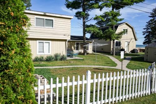 a white picket fence in front of a house at Beach Club of Oscoda - All 4 Beachfront Cottages in Oscoda