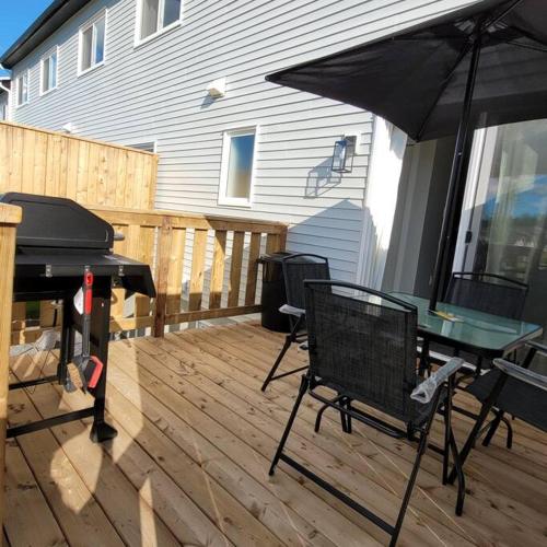 a patio with a table and an umbrella and a grill at The Owusu's Villa in Dieppe