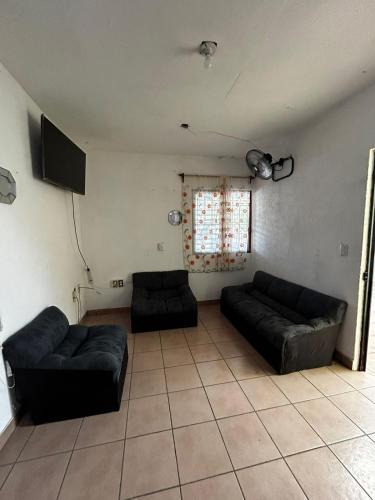 een woonkamer met twee zwarte banken en een raam bij Casa Flor de Mayo in Santa Cruz Huatulco
