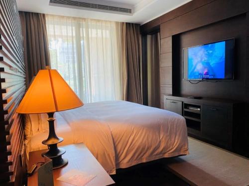 a hotel room with a bed and a television at Raffles Hainan Clear Water Bay in Sanya