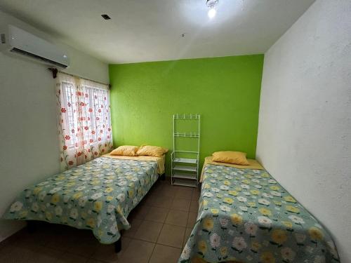two beds in a room with green walls at Casa Flor de Mayo in Santa Cruz Huatulco