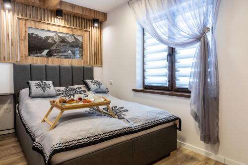a bedroom with a bed with a tray of fruit on it at Apartament TatraVika in Kościelisko