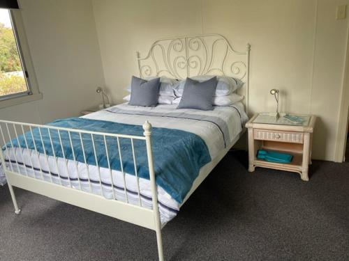 a bedroom with a white bed with blue pillows at Quart Pot House in Stanthorpe
