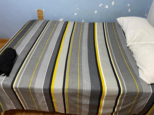 a bed with a striped blanket on top of it at Urcututo House Iquitos in Iquitos