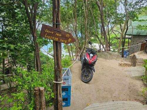 a motorcycle parked next to a sign in the woods at Tao Thong Villa 2 in Ko Tao