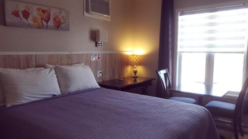 a bedroom with a bed and a desk and a window at Petit Hôtel Amara in La Malbaie