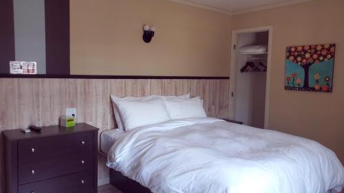 a bedroom with a white bed and a night stand at Petit Hôtel Amara in La Malbaie