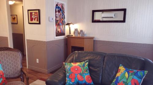 a living room with a leather couch and a table at Petit Hôtel Amara in La Malbaie