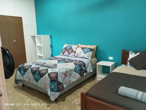 a bedroom with a bed and a blue wall at Habitación familiar in Archidona