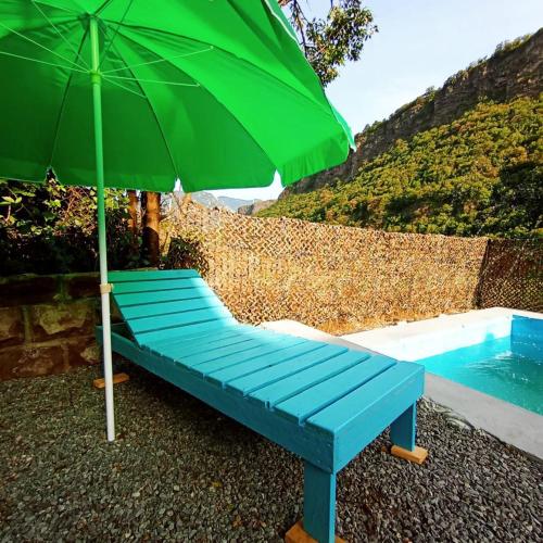 a blue bench with a green umbrella next to a pool at Camping Three poplars by VL in Alaverdi