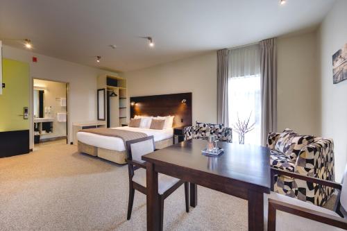 a hotel room with a bed and a table and chairs at Ava Lodge in Lower Hutt