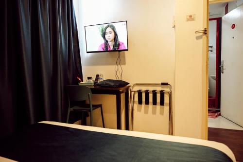 a room with a bed and a desk with a tv on the wall at V Hotel Sri Gombak in Batu Caves