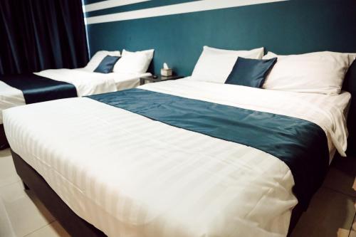 a bedroom with two beds and a blue wall at V Hotel Sri Gombak in Batu Caves