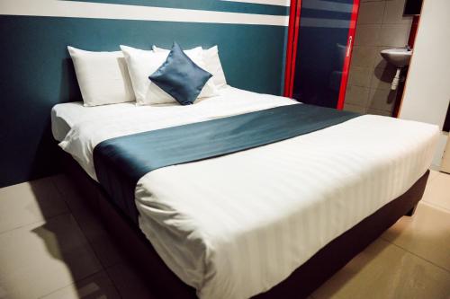 a bedroom with a large bed with blue and white pillows at V Hotel Sri Gombak in Batu Caves