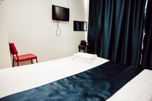 a bedroom with a bed with a television and a chair at V Hotel Sri Gombak in Batu Caves