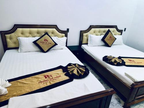 two beds in a room with bows on them at Khách Sạn Phương Nhi in Hue
