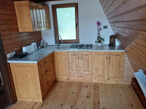 a kitchen with wooden cabinets and a sink and a window at Căsuța Luca in Poienari
