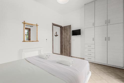 a white bedroom with a bed and a mirror at Anemonisia Skyrian Living in Skiros