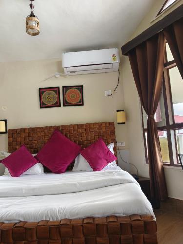 a bedroom with a large bed with purple pillows at Whispering Winds Resort in Dharamshala