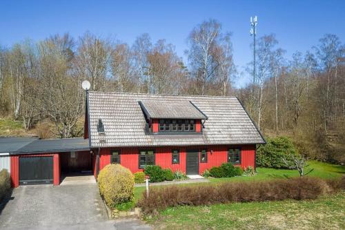 a red house with a black roof and a driveway at Grevie skogsvilla in Grevie