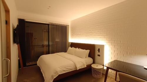 a bedroom with a bed with white sheets and a brick wall at 928 Caxa Juan in Dipolog