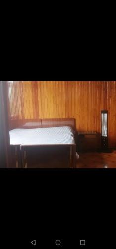 una cama en una habitación con una pared de madera en Eco Hause, en Kobuleti