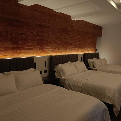 a bedroom with two beds and a brick wall at 928 Caxa Juan in Dipolog