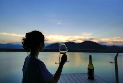 a woman holding a wine glass and a bottle of wine at Huangshan Taiping Lake Muxin Hotel in Fenghuangshan