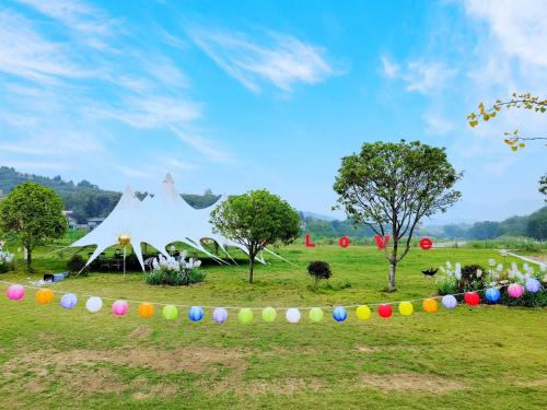 a large white sculpture in a field with colorful eggs at Zhangjiajie Cliff Flower RV Tent Hotel in Sanguansi