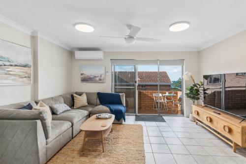 a living room with a couch and a table at North Beach Escape - Balcony Sunrises and Ocean Walks in Wollongong