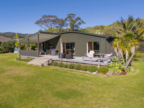 a home with a large yard in front of it at Wai Whare - Kūaotunu Holiday Home in Whitianga