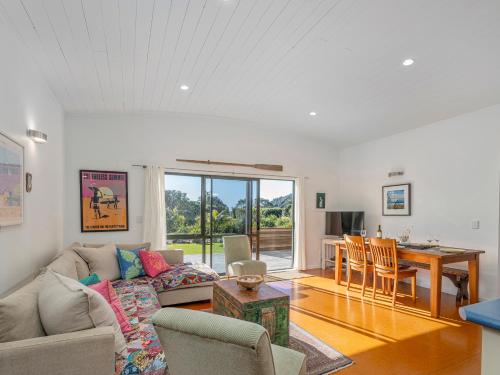 a living room with a couch and a table at Wai Whare - Kūaotunu Holiday Home in Whitianga
