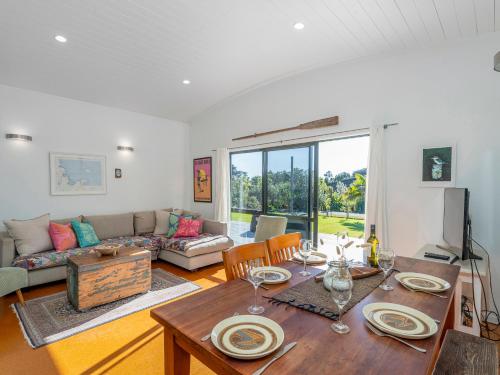 a living room with a table and a couch at Wai Whare - Kūaotunu Holiday Home in Whitianga