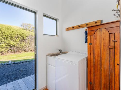 a laundry room with a washing machine and a window at Wai Whare - Kūaotunu Holiday Home in Whitianga
