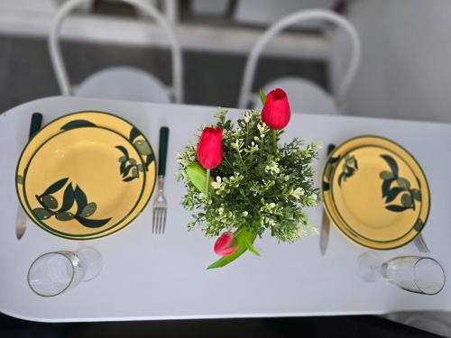 deux assiettes jaunes et un vase de fleurs sur une table dans l'établissement Séjour à 10 minutes du Château de Versailles et 20 minutes de Roland-Garros- Votre suite avec lit King Size, à Le Chesnay