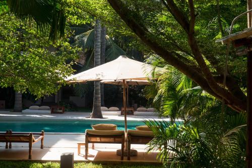 a pool with an umbrella and a chair and a table at Palm Garden ECO Boutique Hotel No Kids under 12 in Watamu