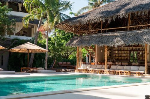 a resort with a swimming pool with chairs and umbrellas at Palm Garden ECO Boutique Hotel No Kids under 12 in Watamu