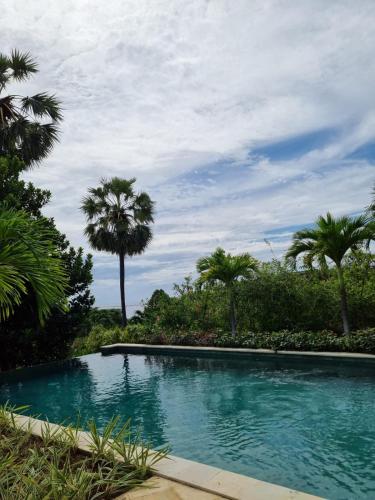 a swimming pool with palm trees in the background at Villa Ponjok Batu Residence in Bukti