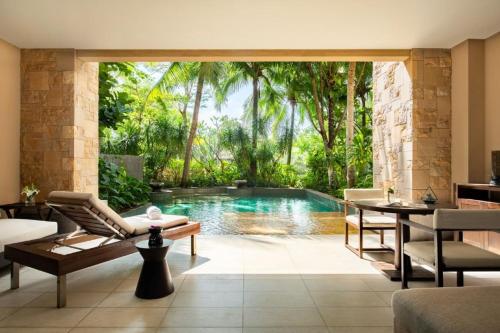 a swimming pool in a room with a table and chairs at Raffles Hainan Clear Water Bay in Sanya