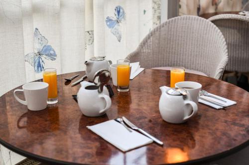 een houten tafel met kopjes en kannen sinaasappelsap bij Hotel K'Loys in Paimpol
