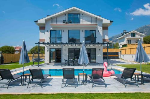 eine Villa mit Pool und Liegen und ein Haus in der Unterkunft Villa Bahar 2 Triplex Luxury New Villa in Fethiye Oludeniz! in Ovacık