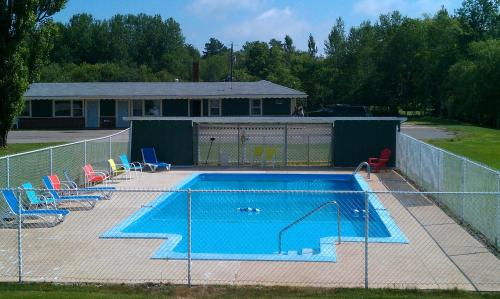 a swimming pool behind a fence with chairs around it at Middleton Motel & Suites in Middleton