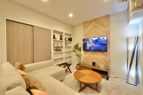 a living room with a white couch and a flat screen tv at Branchera Naha Akebono Premist R65 in Nakanishi