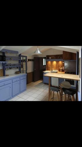 une cuisine avec des armoires bleues et une table et des chaises dans l'établissement Les Grands Bois Gite et cabane, à Thézac