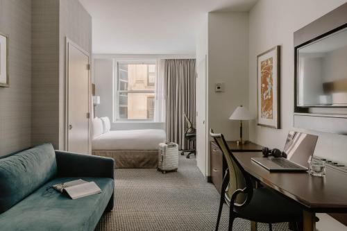 a hotel room with a couch and a desk with a laptop at Club Quarters Hotel Faneuil Hall, Boston in Boston