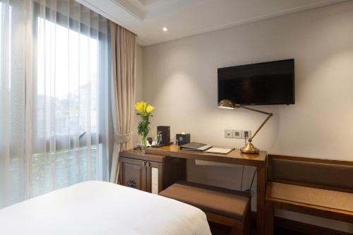 a hotel room with a desk with a bed and a television at Peridot Gallery Classic Hotel in Hanoi