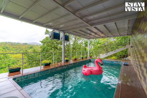 a swimming pool with a pink swan in the water at The Glasscape by StayVista - Hillside getaway with Pool and Indoor games in Nashik