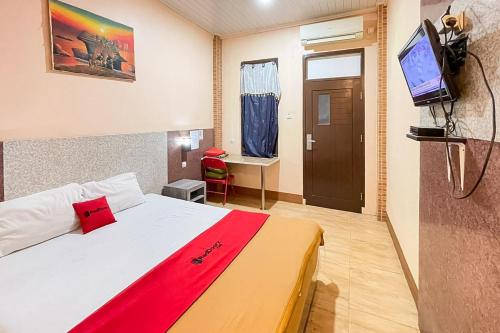 a bedroom with a white bed with a red blanket at RedDoorz Syariah near Mall Of Serang in Kumprung